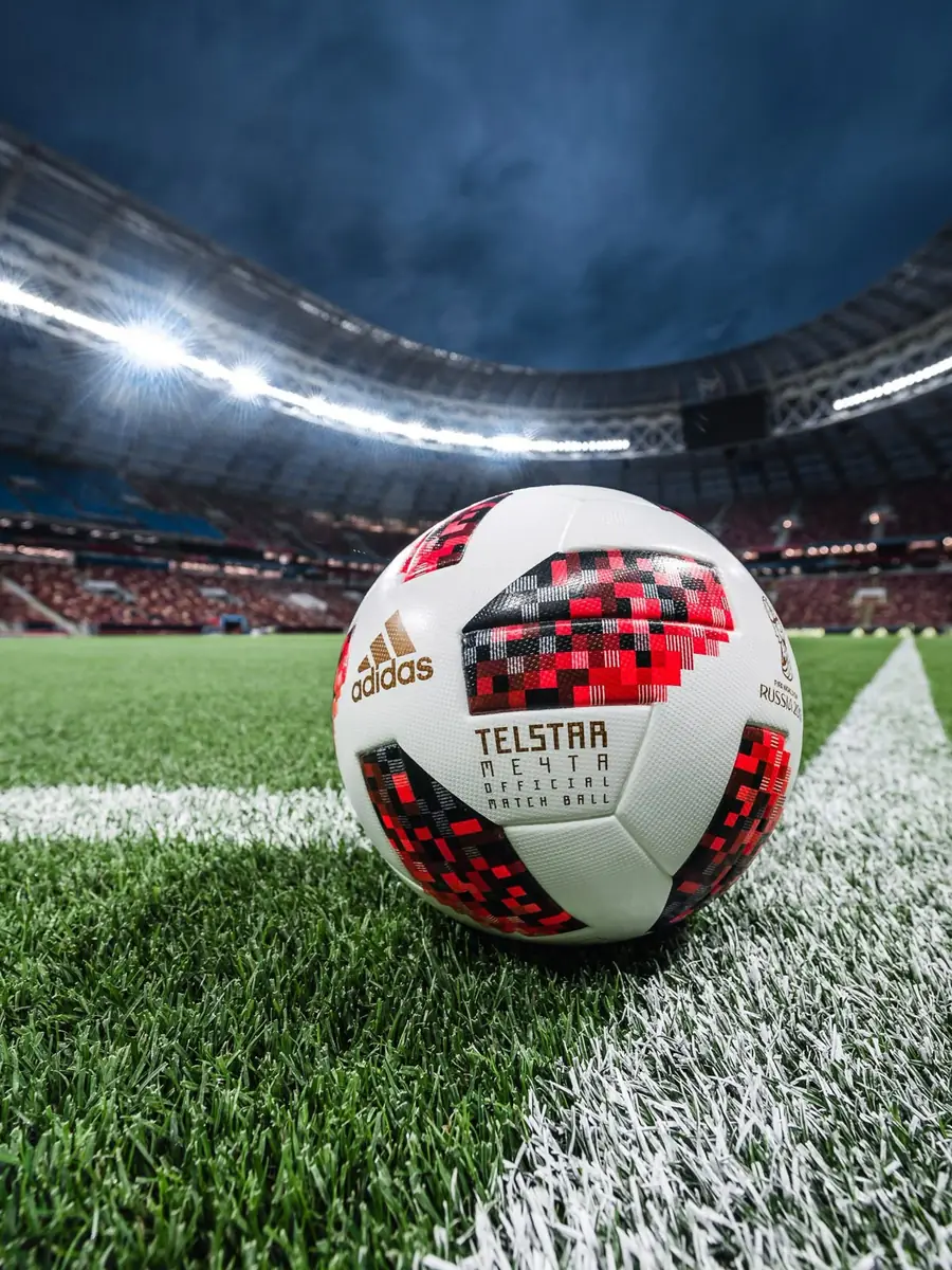 A football on the grass of a floodlit stadium at night